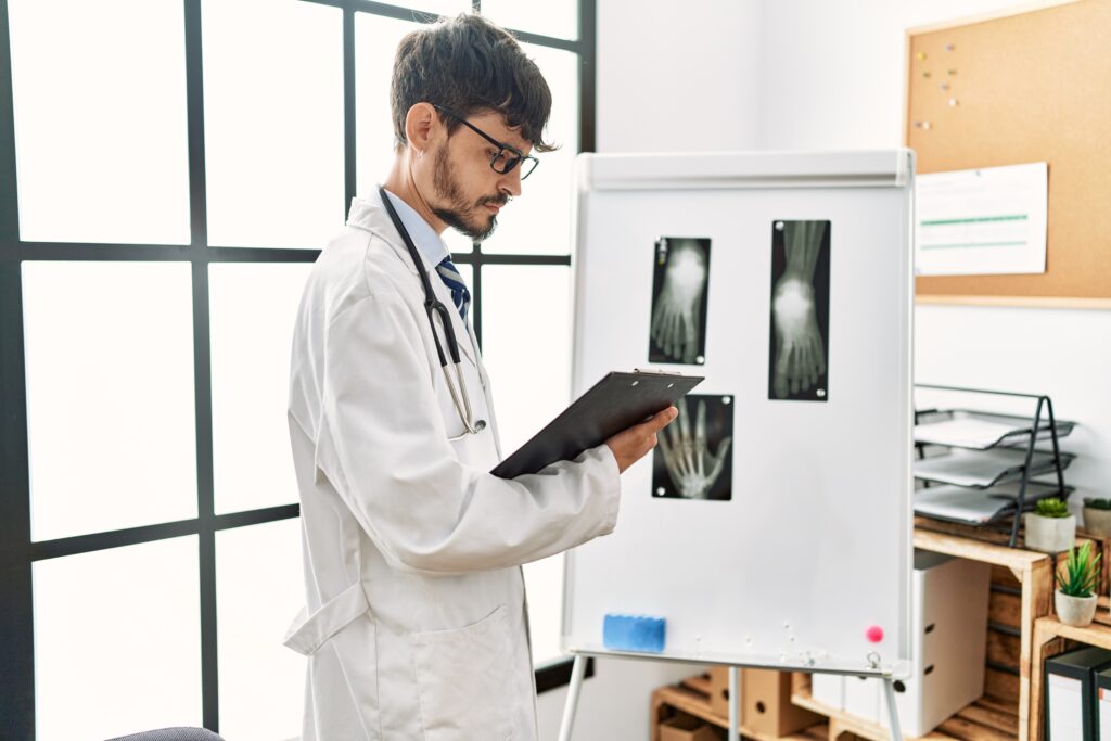Young hispanic doctor man looking xray working at clinic